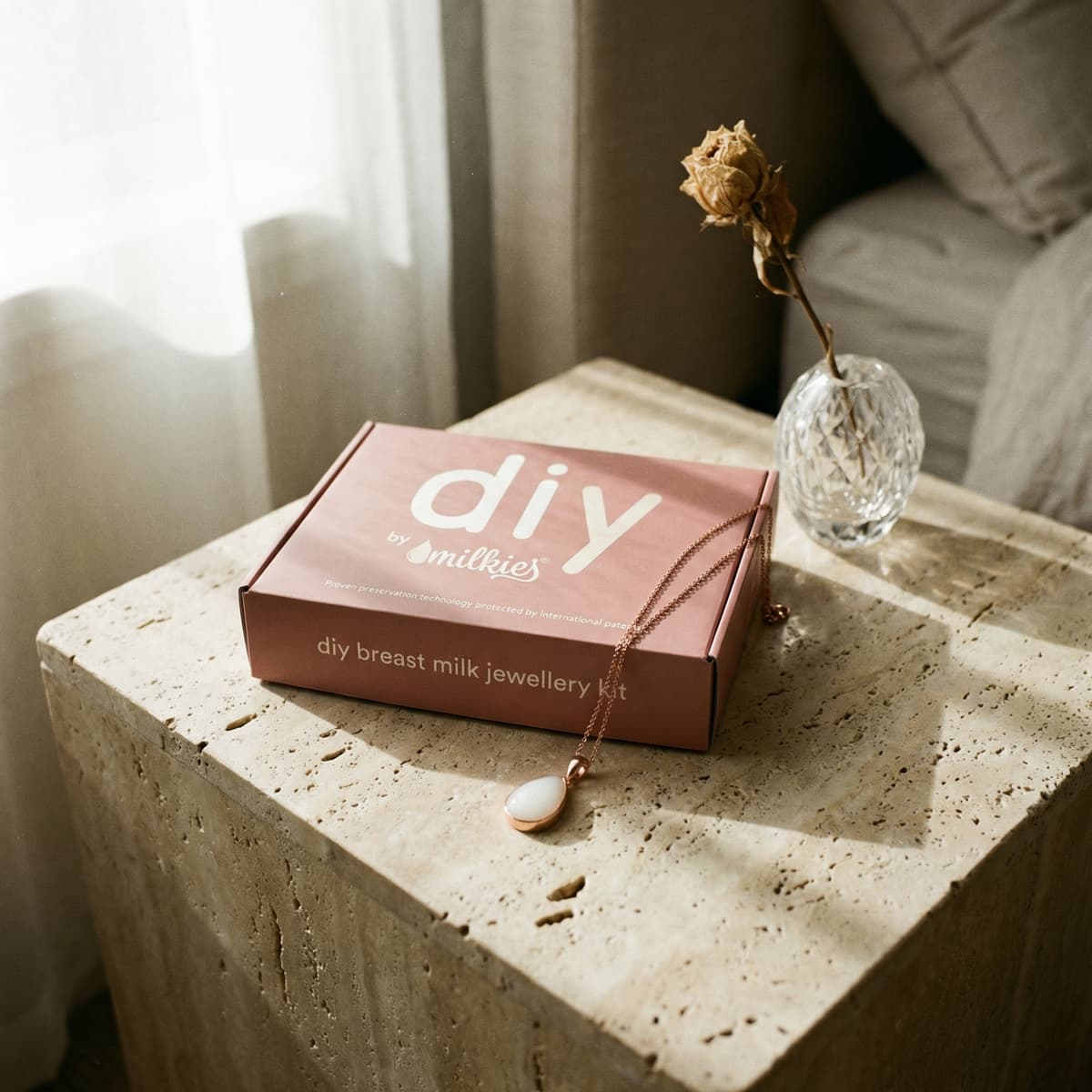 Coffret DIY by MILKIES de bijou au lait maternel, une idée de cadeau naissance maman, posé sur une table avec un collier pendentif et un vase en verre.
