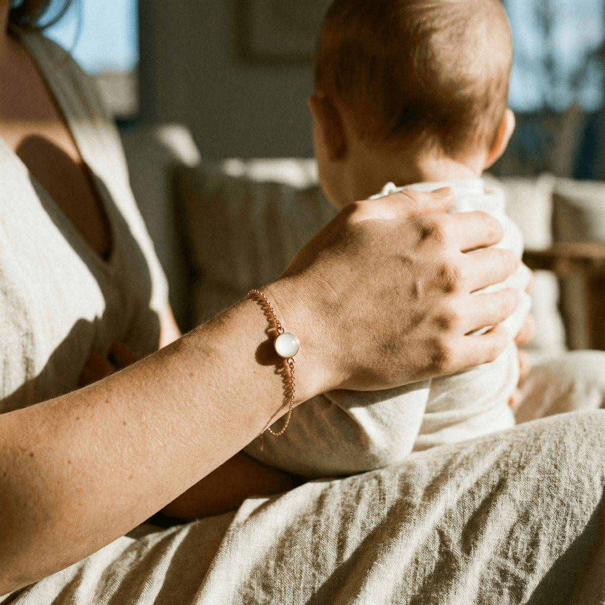 Maman tenant son bébé avec un bracelet souvenir au poignet, illustrant pourquoi choisir un kit diy bracelet lait maternel pour créer chez soi un bijou intime et durable.